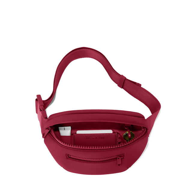 Dagne Dover Ace Fanny Pack in spice red unzipped, exposing the interior pockets. hover