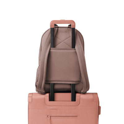 Dagne Dover large Dakota Neoprene Backpack in pink strapped to luggage with the neoprene luggage-handle sleeve.