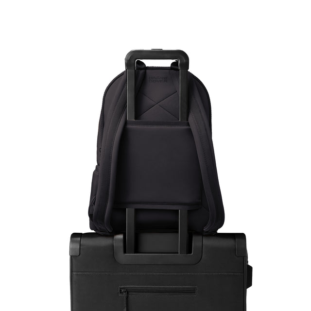 Dagne Dover large Dakota Neoprene Backpack in black strapped to luggage with the neoprene luggage-handle sleeve.