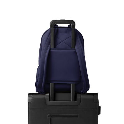 Dagne Dover large Dakota Neoprene Backpack in dark blue strapped to luggage with the neoprene luggage-handle sleeve.