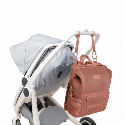 Dagne Dover Large Indi Diaper Backpack in dust pink air mesh attached to a stroller.