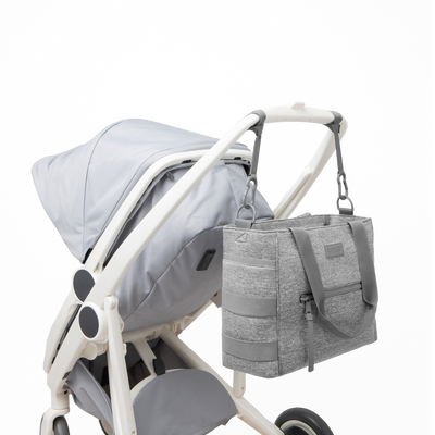 Dagne Dover large Wade Diaper Tote in grey strapped to the handle of a stroller.