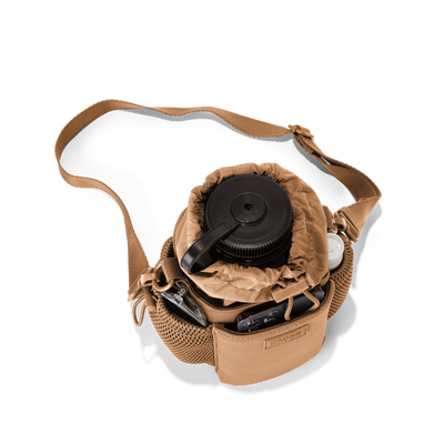 Dagne Dover Sloan Water Bottle Sling in camel brown seen from above containing a water bottle and accessories hover