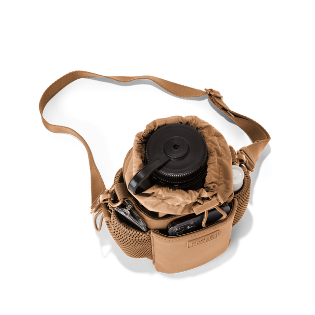 Dagne Dover Sloan Water Bottle Sling in camel brown seen from above containing a water bottle and accessories hover