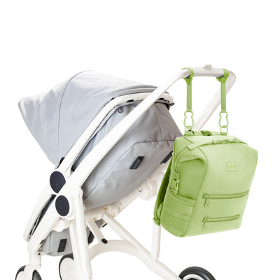 Dagne Dover Medium Indi Diaper Backpack in a vibrant, creamy green attached to a stroller.