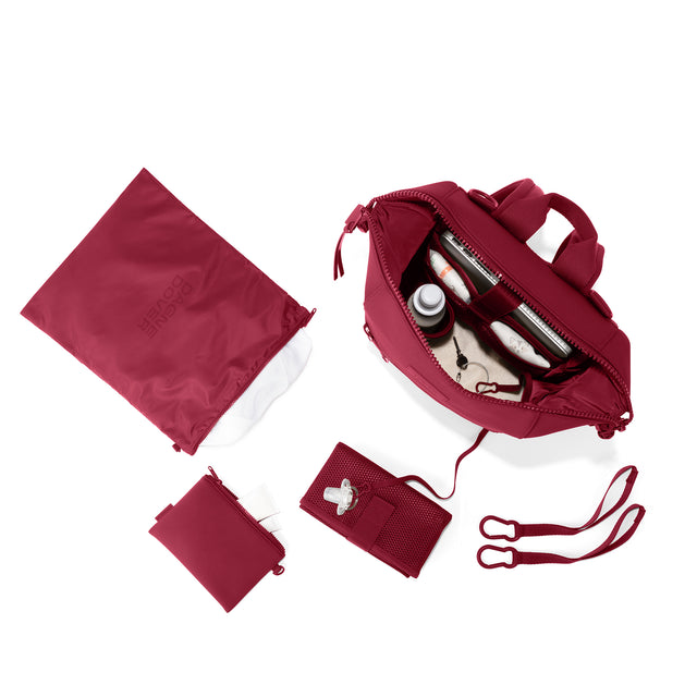 Dagne Dover Medium Indi Diaper Backpack in a punchy, saturated deep red showing it's water resistant bag, interior pockets, and changing mat. hover