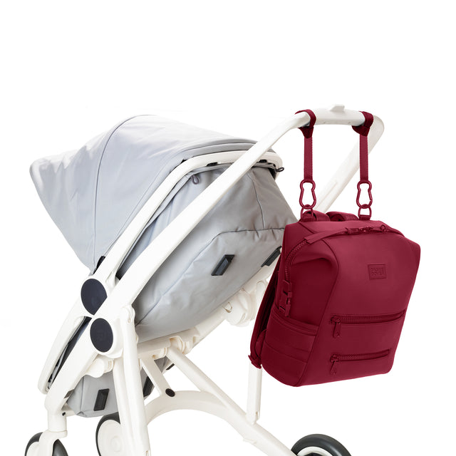 Dagne Dover Medium Indi Diaper Backpack in a punchy, saturated deep red attached to a stroller.