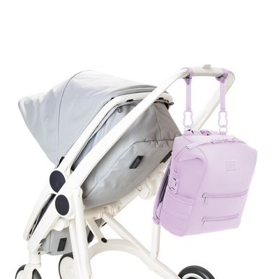 Dagne Dover medium Indi Diaper Backpack in a soft purple with grey undertones attached to a stroller.
