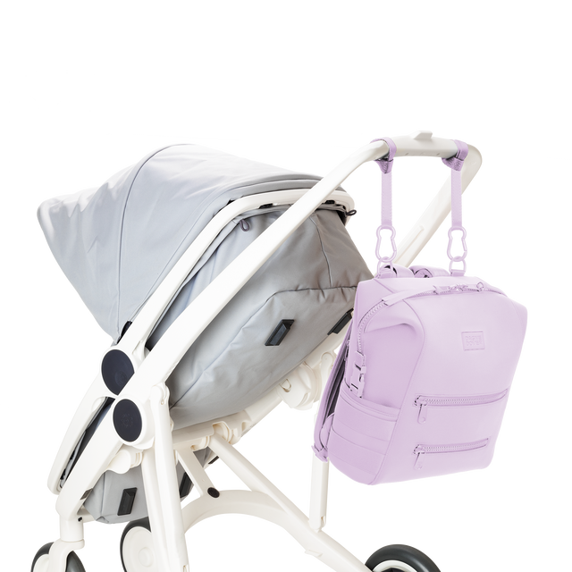 Dagne Dover medium Indi Diaper Backpack in a soft purple with grey undertones attached to a stroller.
