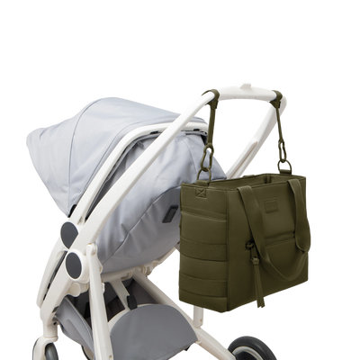 Dagne Dover large Wade Diaper Tote in dark green strapped to the handle of a stroller.