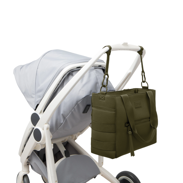 Dagne Dover large Wade Diaper Tote in dark green strapped to the handle of a stroller.