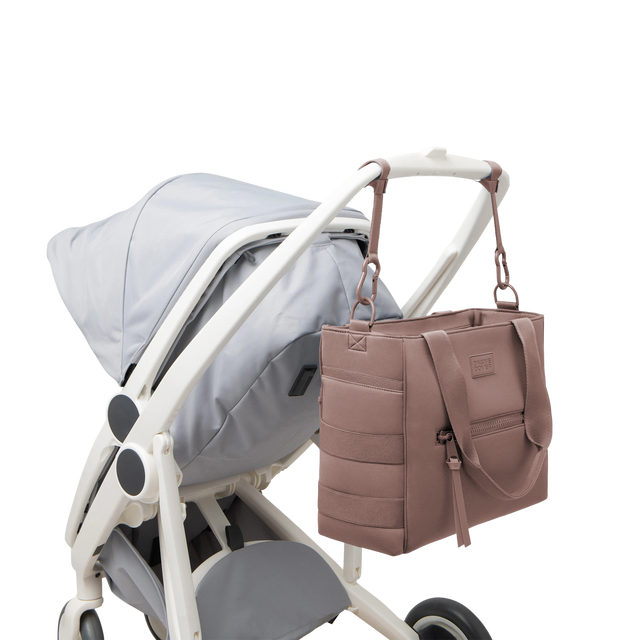 Dagne Dover large Wade Diaper Tote in pink strapped to the handle of a stroller.