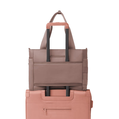 Dagne Dover large Wade Diaper Tote in pink with the neoprene luggage sleeve attached to a suitcase handle.