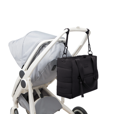 Dagne Dover large Wade Diaper Tote in black strapped to the handle of a stroller.