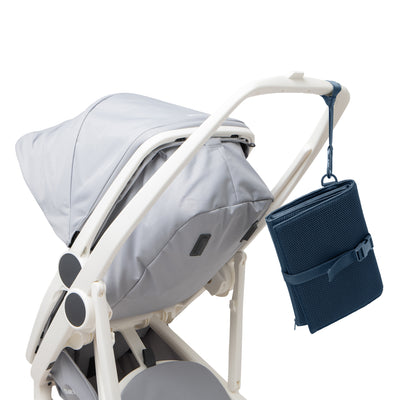 Dagne Dover Joey Changing Kit in moonlight blue strapped to the handle of a stroller.