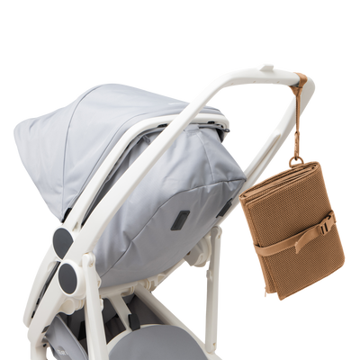 Dagne Dover Joey Changing Kit in camel brown strapped to the handle of a stroller.