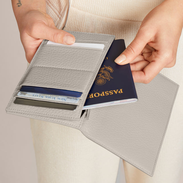 Someone taking their passport out of the Accordion Travel Wallet in white. 